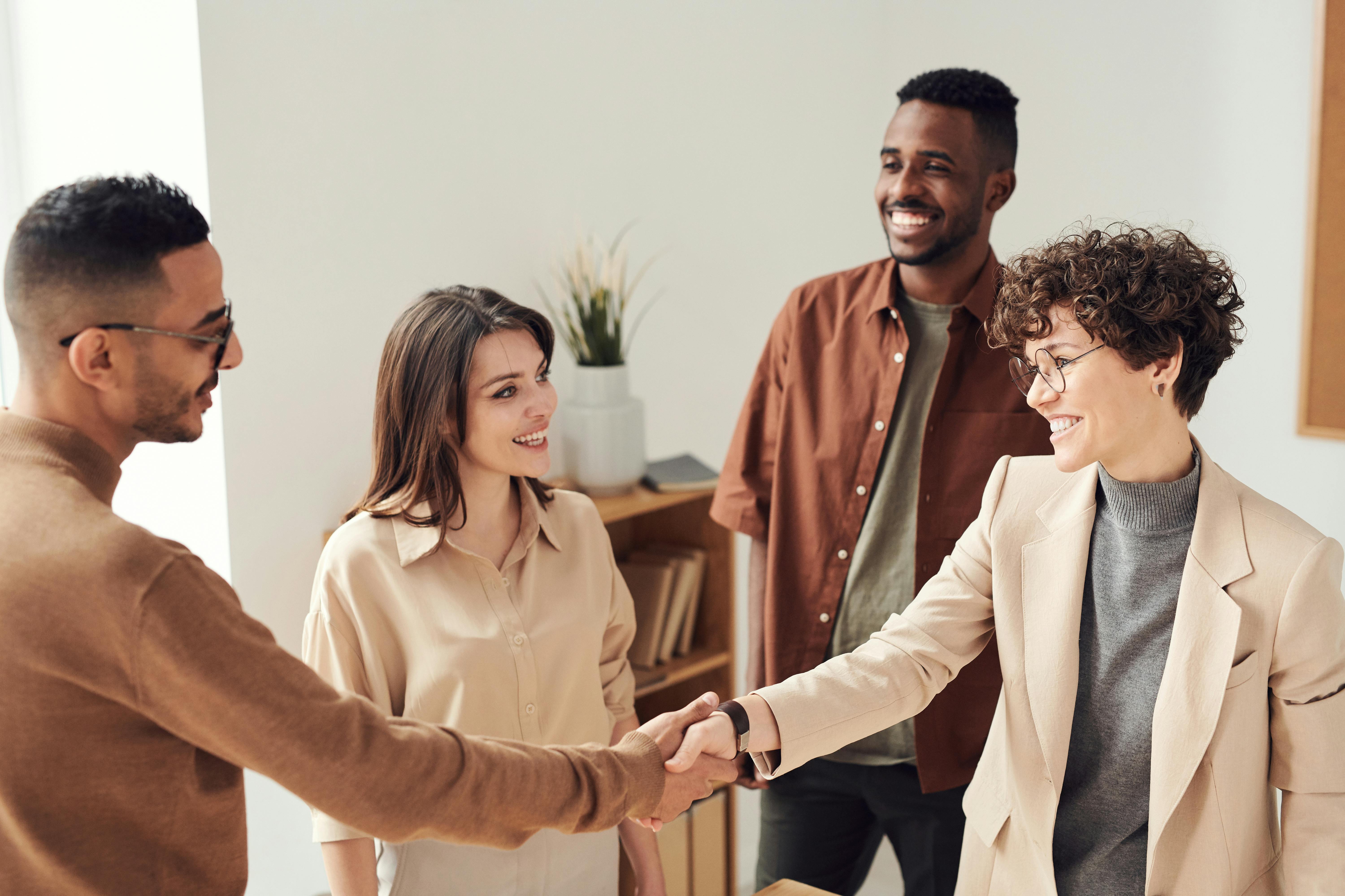 Group of adult professionals shaking hands and smiling.